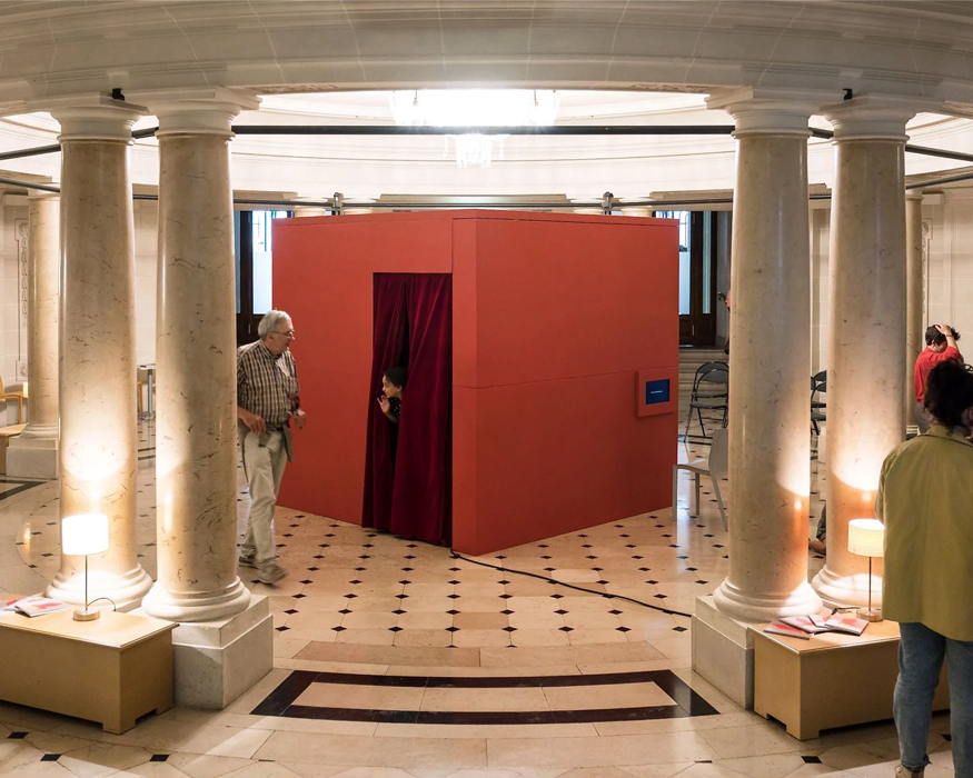 L'isoloir est au centre d'un espace culturel. Il s'agit d'un cube rouge dans lequel un individu entre et va modifier une photo de chez lui, et modifier son environnement sonore.